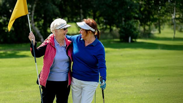 Two women hugging as they play golf
