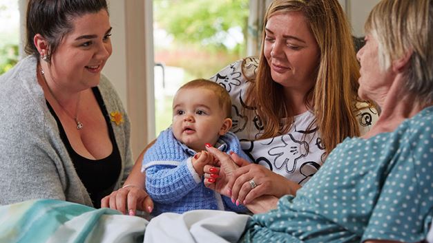 Jacqui in a hospice bed surrounded by her two daughters Kelly and Emma