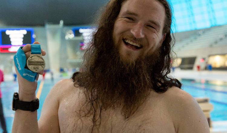 Bearded swimmer smiles as he holds up his medal at Swimathon 2018 in support of Marie Curie and CRUK